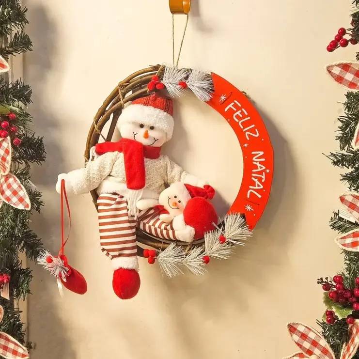 Guirlanda de cipó com bonecos de neve, ramos brancos e placa vermelha em arco com a escrita "Feliz Natal".