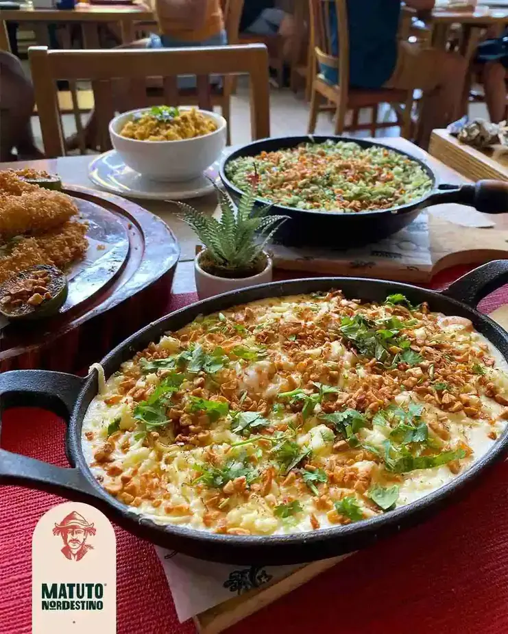 468867871 448556168283460 394091951467420919 n Pratos típicos nordestinos do restaurante Matuto Nordestino em frigideiras de ferro sobre mesa de restaurante.