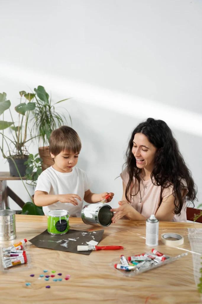 mom showing kid how reuse materials creative ways Mãe e filho criando arte com latas recicladas.