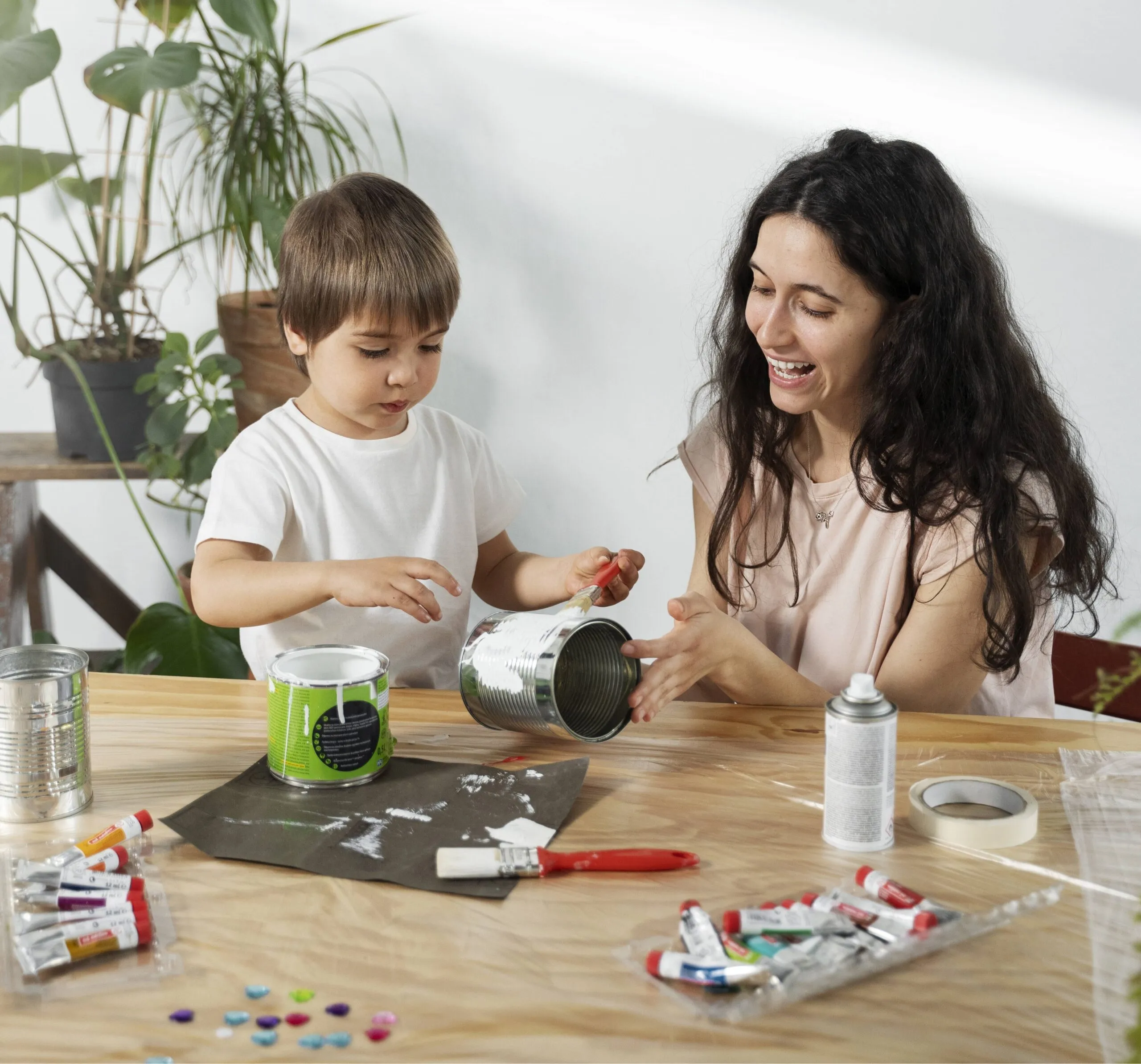 Mãe e filho criando arte com latas recicladas.