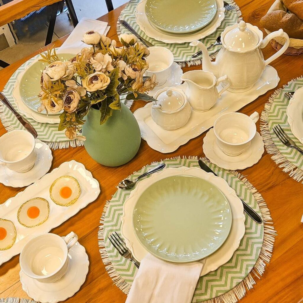 SaveClip.App 460295383 1914395059032885 6463959815772129515 n Mesa posta com louças brancas e flores decorativas.