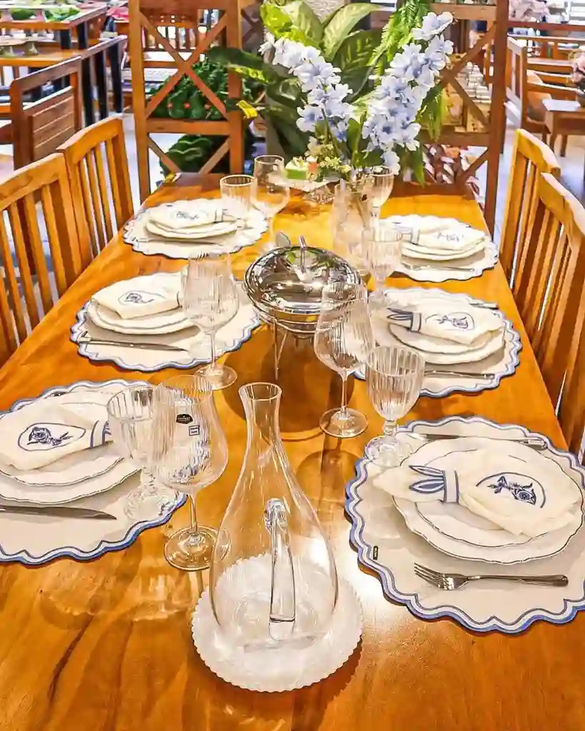 Mesa posta com louça elegante e flores decorativas.