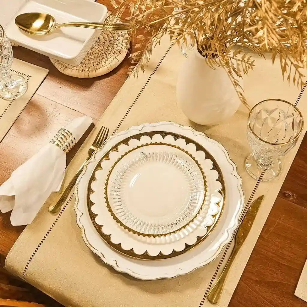 Mesa posta elegante com pratos e talheres dourados.