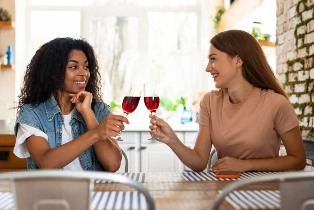 smiley female friends toasting together glass wine Duas mulheres brindando com taças de vinho tinto
