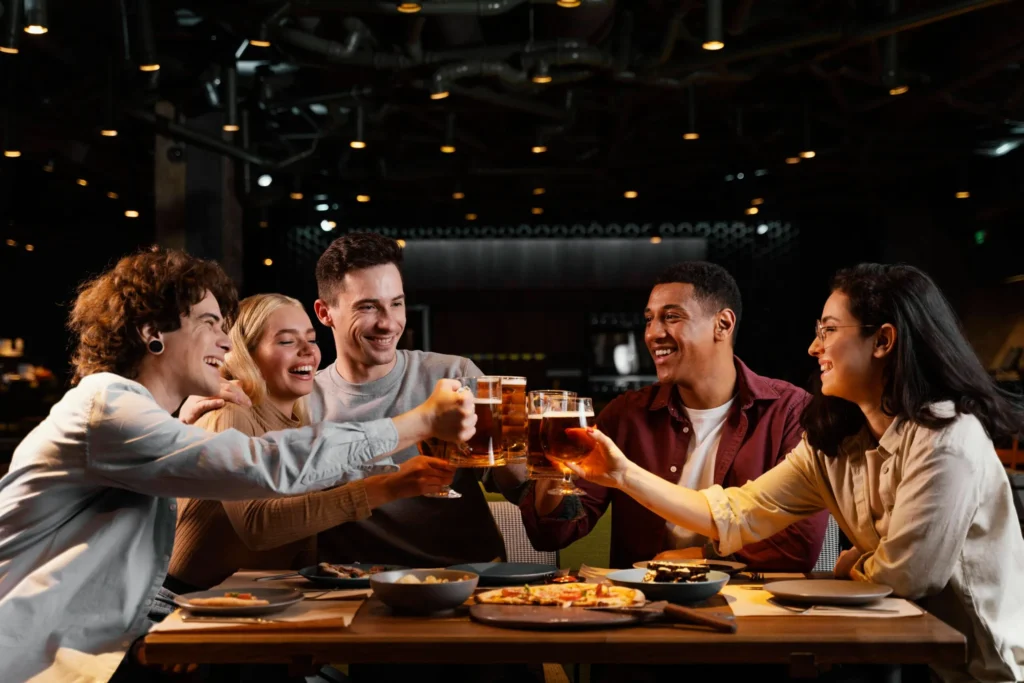 medium shot happy friends with beer mugs Grupo de amigos fazendo brinde em jantar