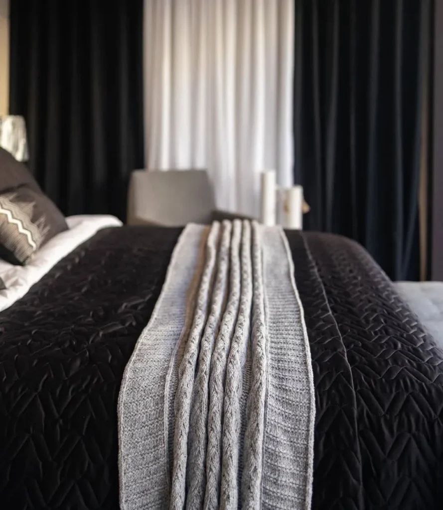 Cama com cobertor cinza em quarto moderno.
