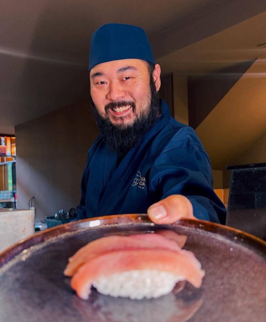 Chef de sushi apresentando sushi de atum.