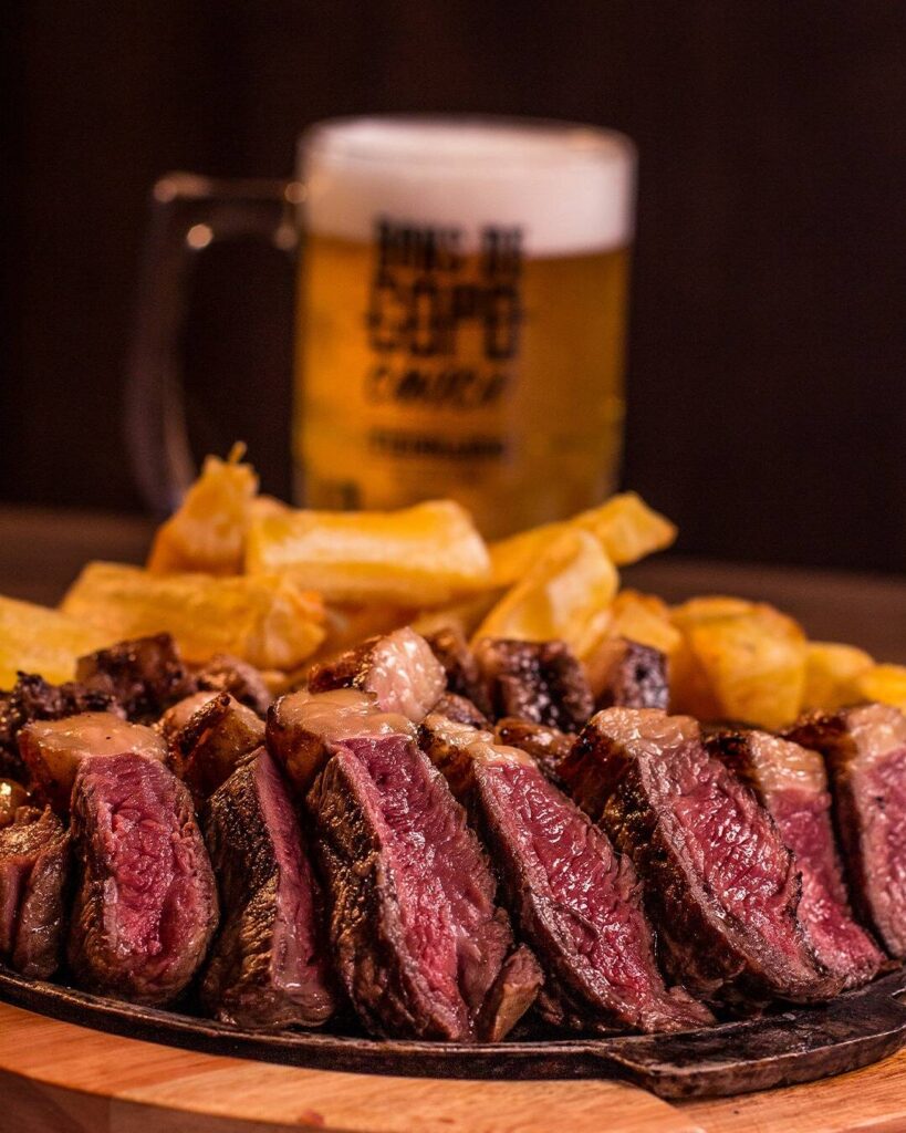 Picanha suculenta acompanhada de batatas fritas e cerveja