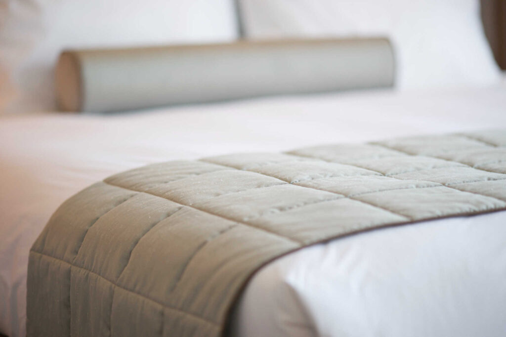 Cama com colcha de cama cinza e travesseiro