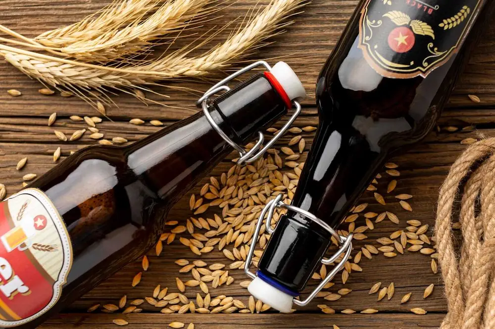 Duas garrafas de cerveja sobre grãos de cevada.