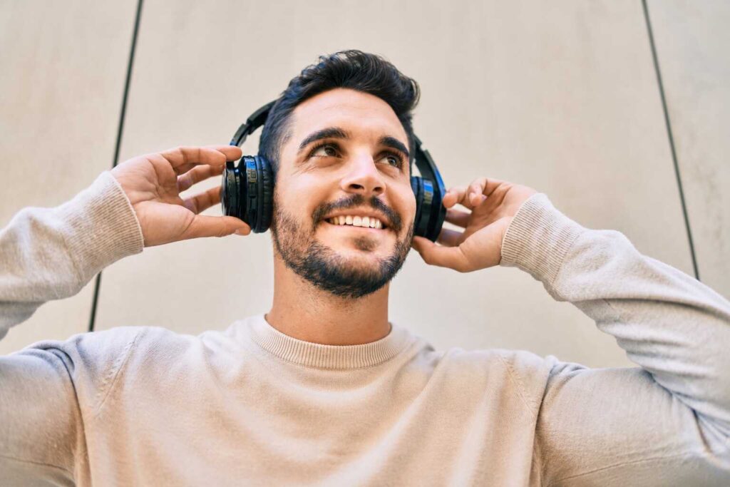 Homem sorrindo enquanto ouve música com fones de ouvido.