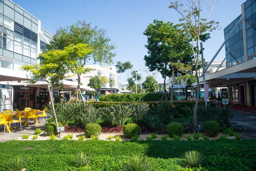 Área verde em shopping ao ar livre com árvores e bancos