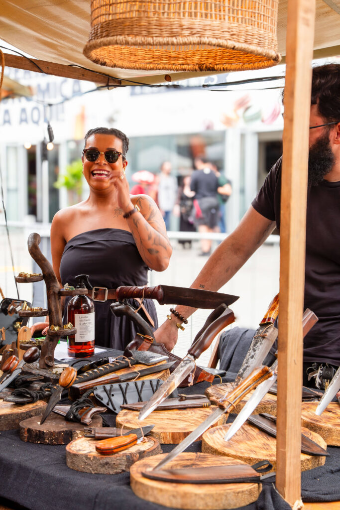 Feira de artesanato com facas artesanais e pessoas felizes.