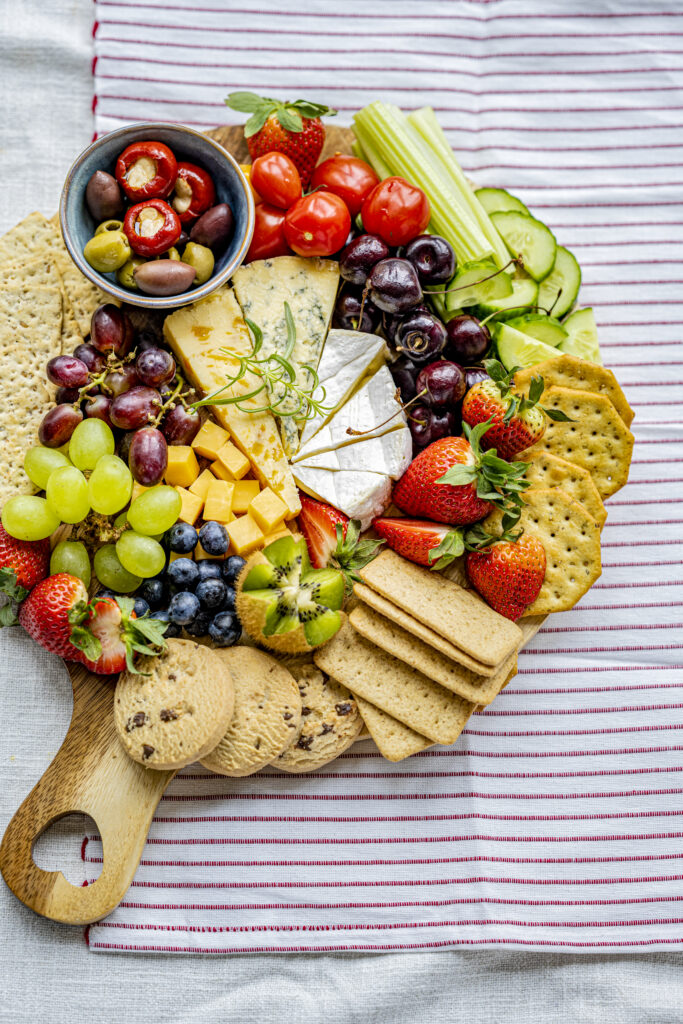 tabua de queijos com frutas frescas e biscoitos Prato colorido de frios e frutas frescas