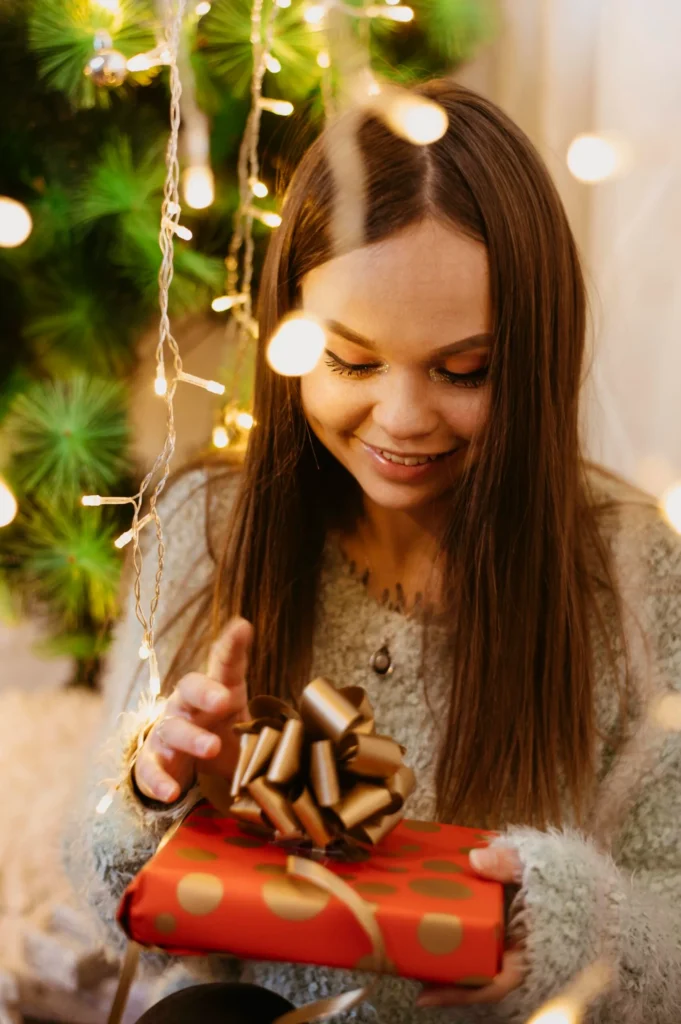 jovem mulher segurando uma arvore de natal Menina sorridente abrindo presente decorado