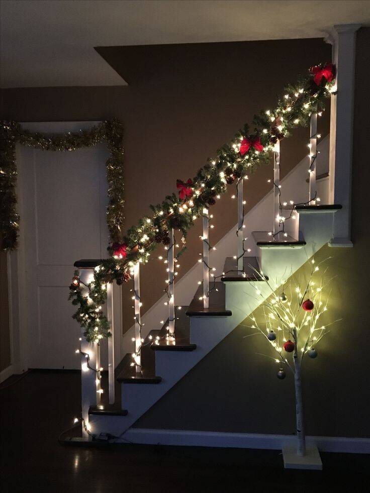 Escada decorada com luzes de Natal e galhos verdes