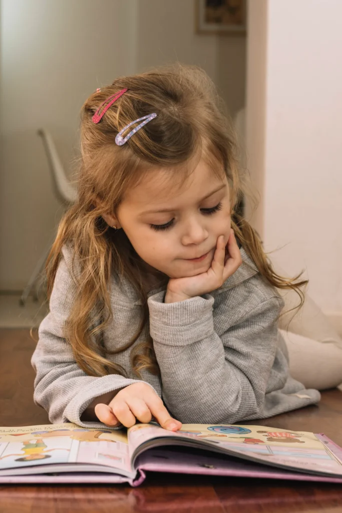 linda menina olhando fotos no livro Criança lendo um livro infantil