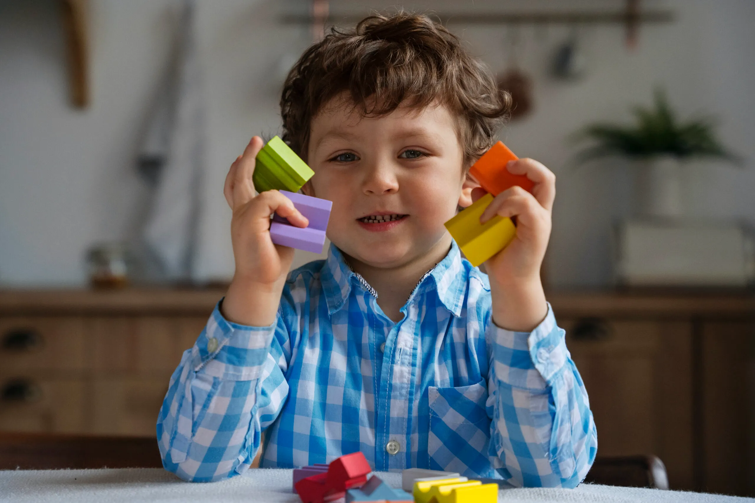Menino sorridente com blocos de brinquedo na mão