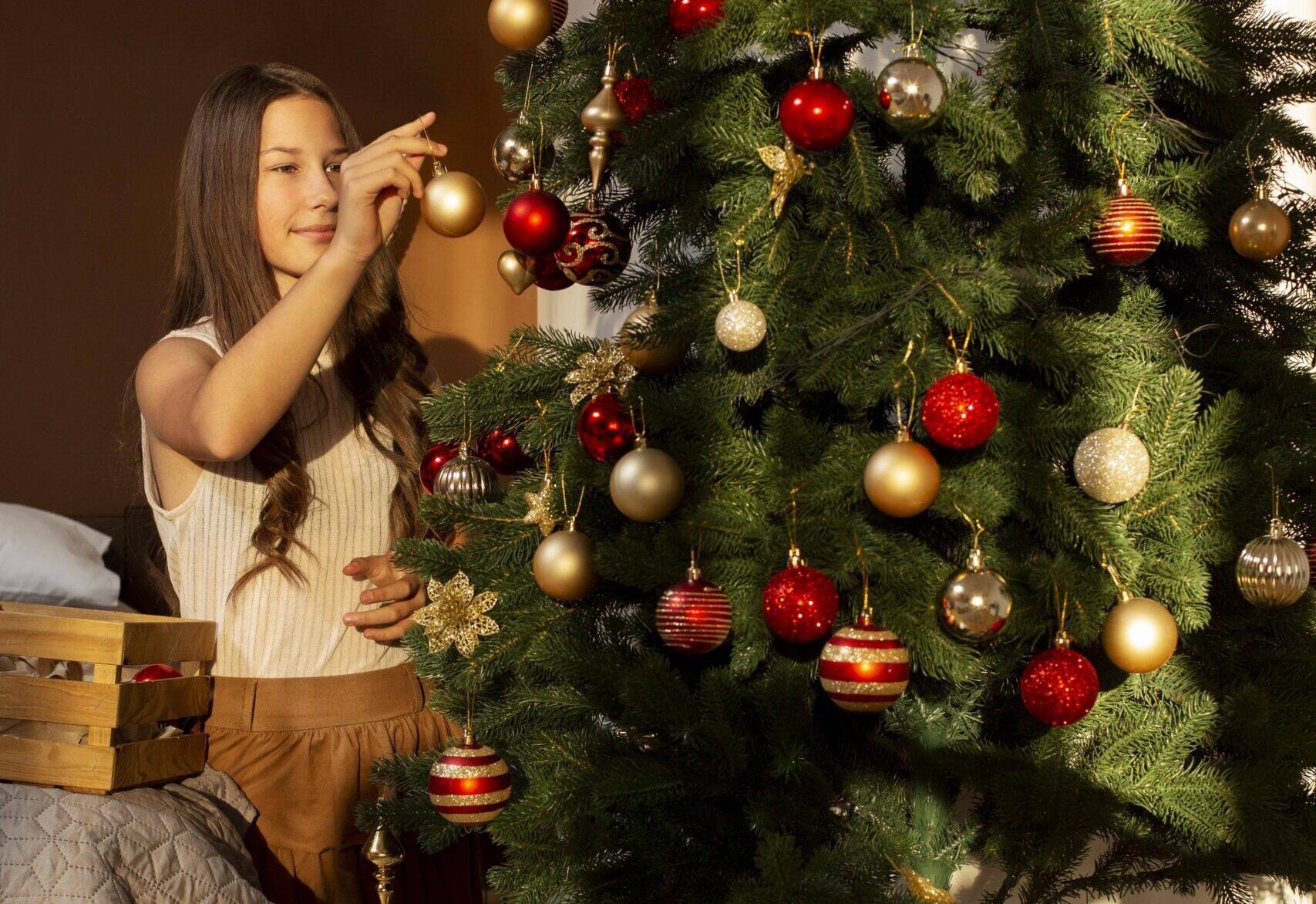 Criança enfeitando a árvore de Natal com bolas coloridas