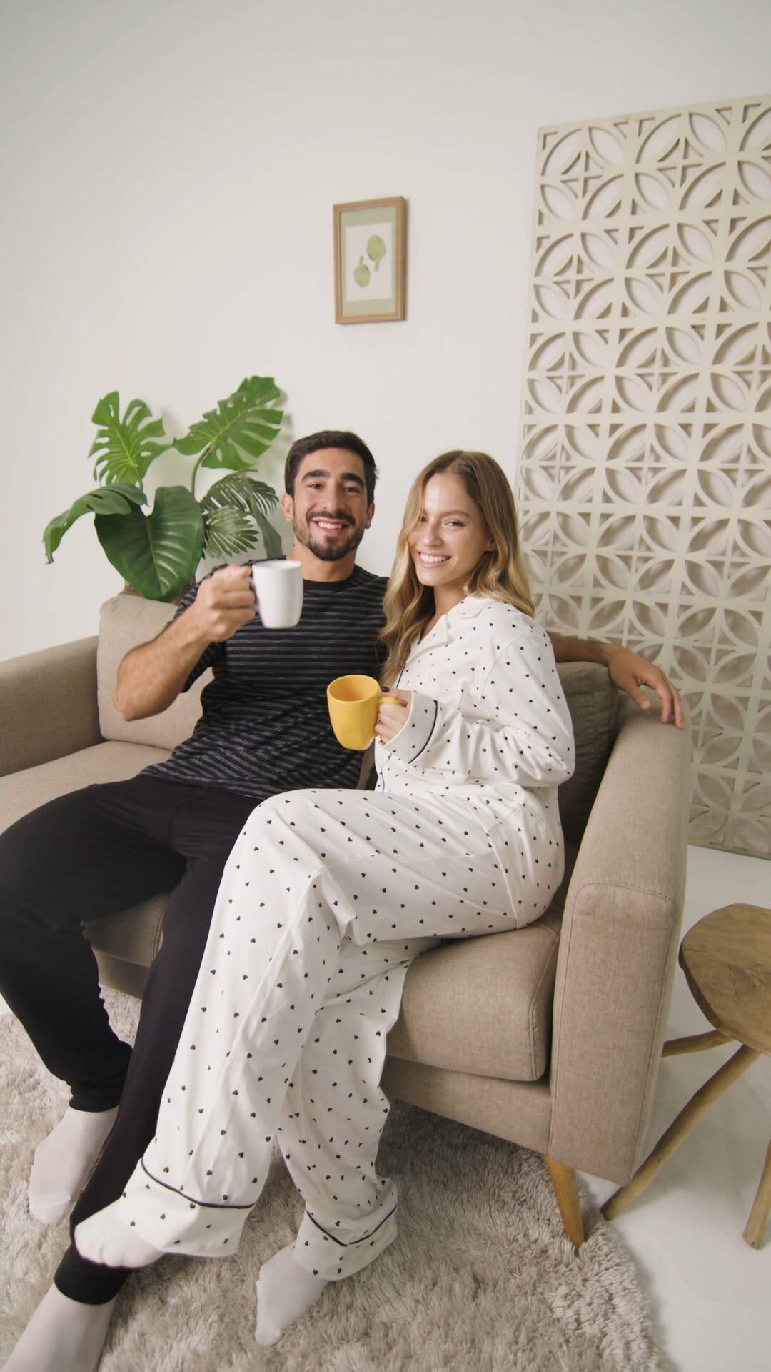 Casal relaxando em sofá com canecas de café
