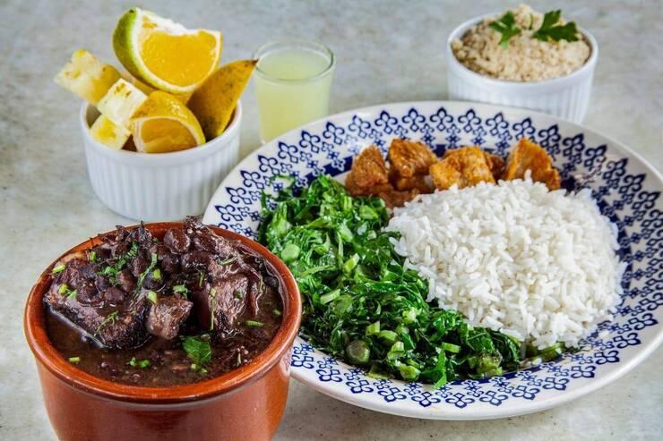 Prato típico com feijoada, arroz e acompanhamentos frescos