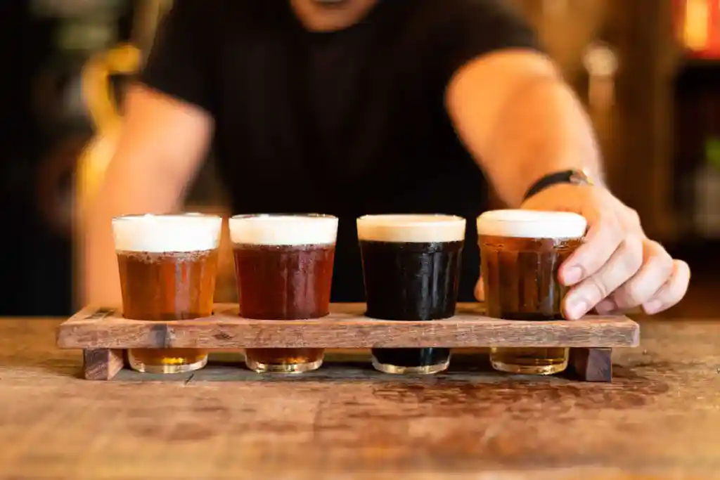 Quatro copos de cerveja em tábua de madeira.