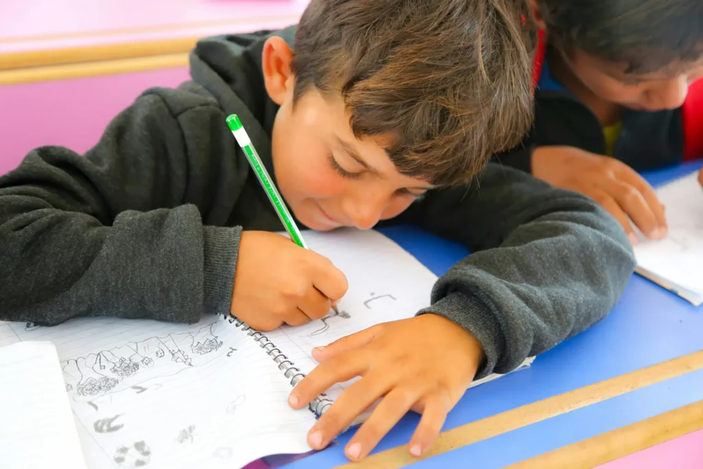 Criança desenhando em caderno na escola