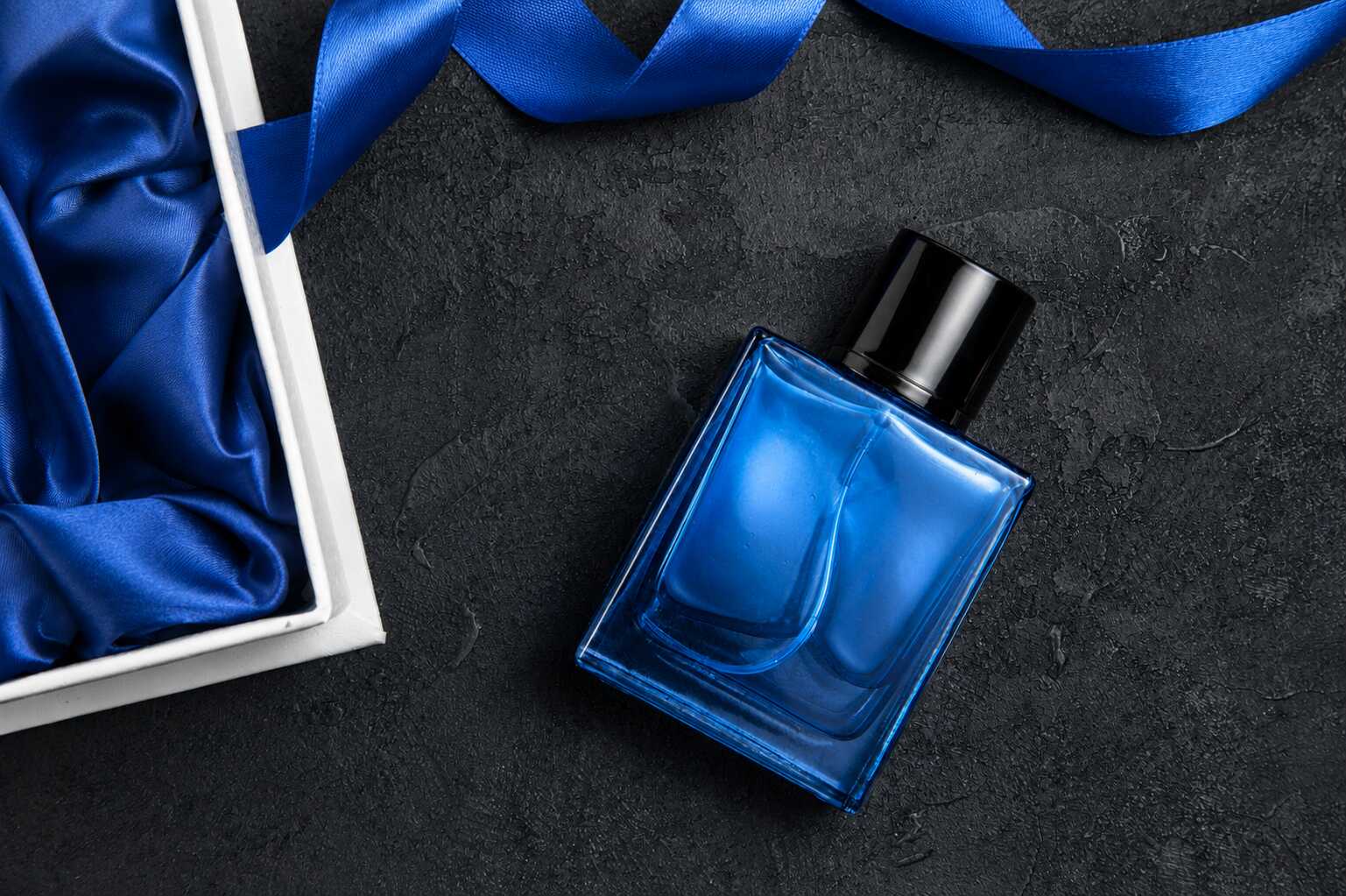 Frasco de perfume azul ao lado de fita azul