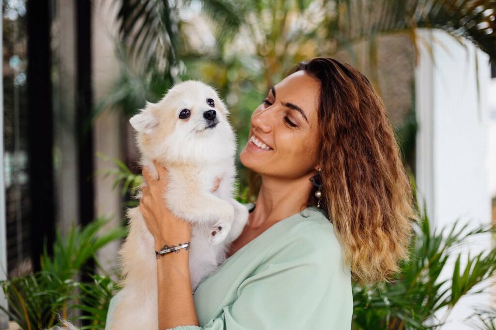 7feca9e5 outdoor portrait curly european tanned woman holds happy pet dog pomeranian spitz 343596 1353