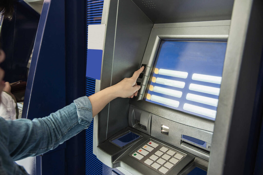 Pessoa utilizando caixa eletrônica para realizar transação