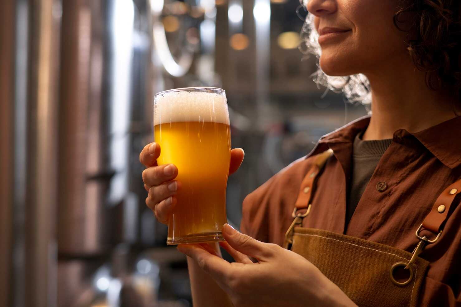 Mulher segurando copo de cerveja artesanal.