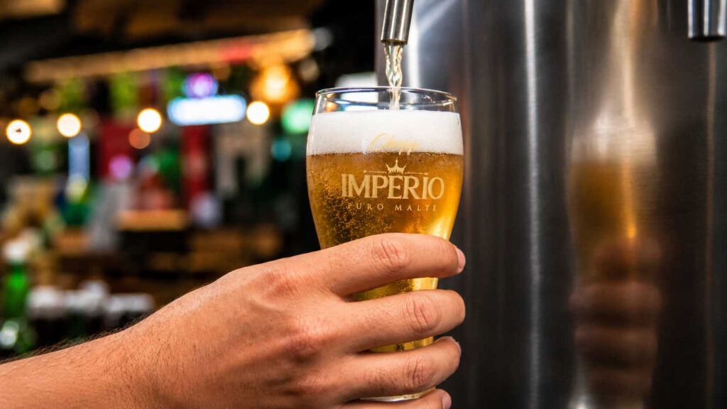 fbf2aeaa ChatGPTImage9dejul.de202617 22 48 Copo de cerveja sendo servido em bar com ambiente descontraído.