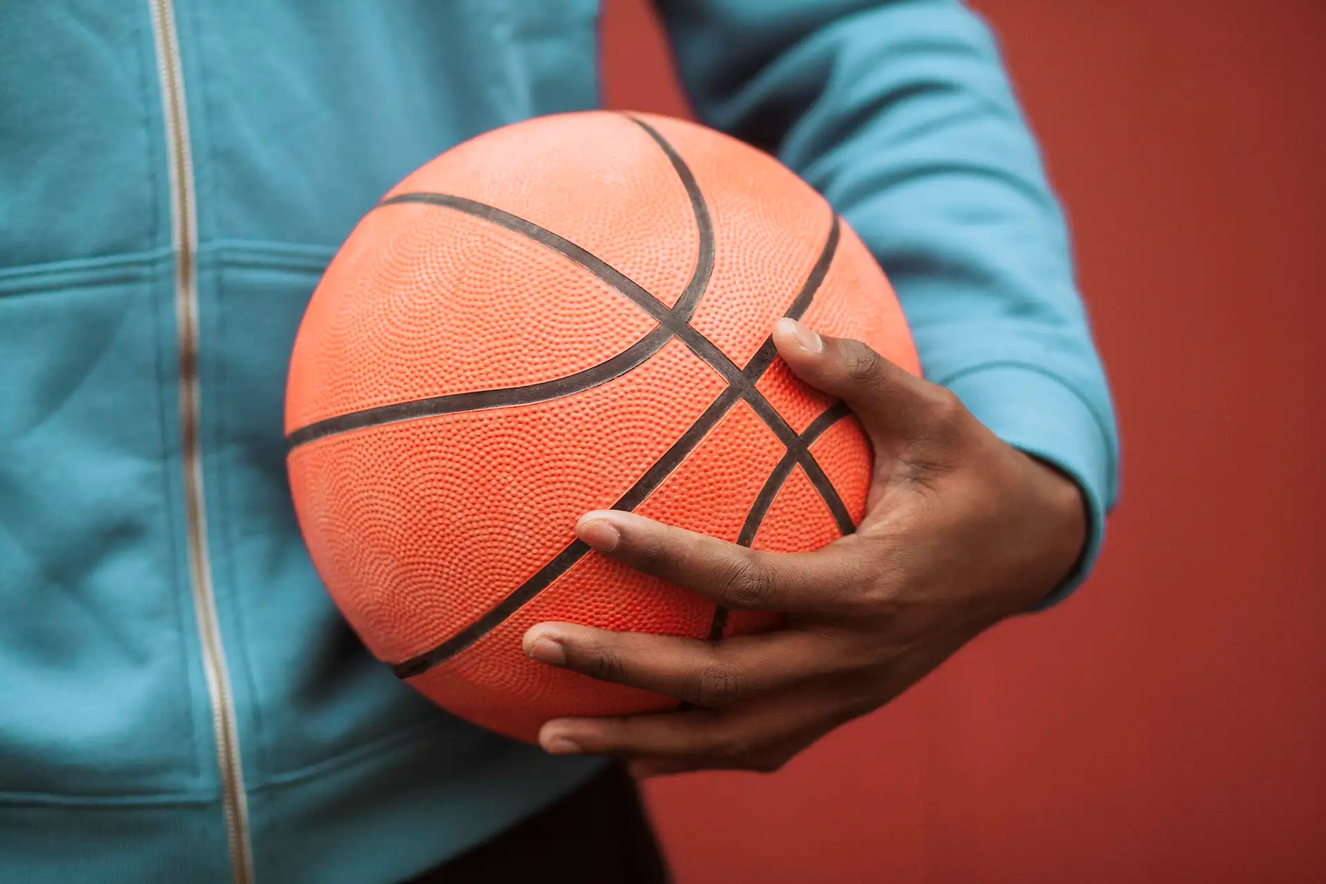 Homem segurando bola de basquete laranja.