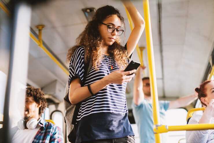 Jovem usando celular em ônibus urbano.