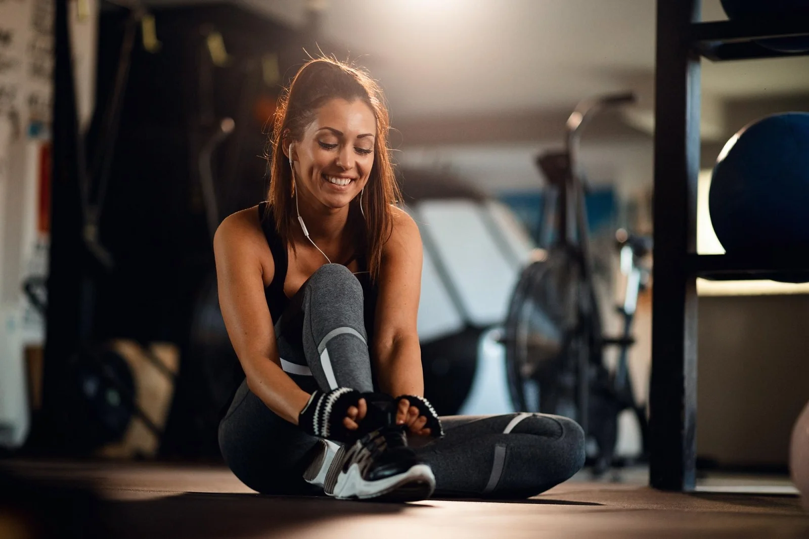 Mulher se alongando em academia com sorriso.